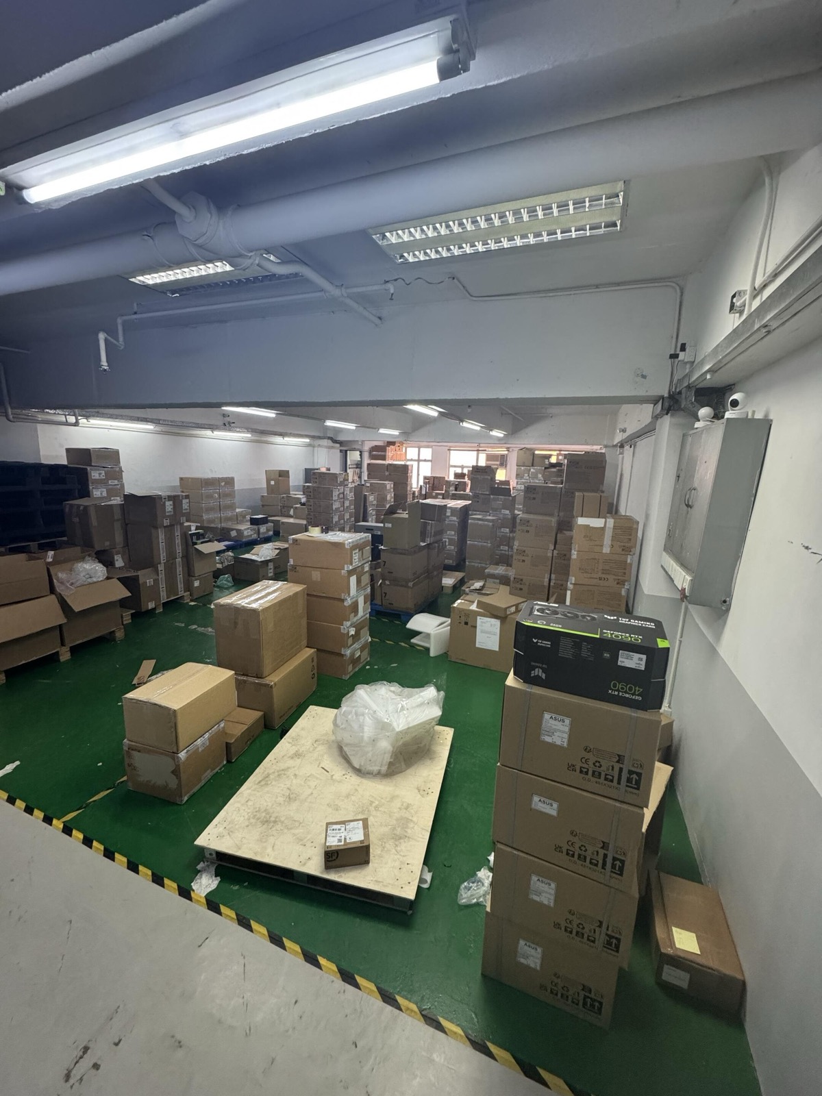 Taiwan partner warehouse with large inventory storage area, stacked cardboard boxes, green flooring, and loading area