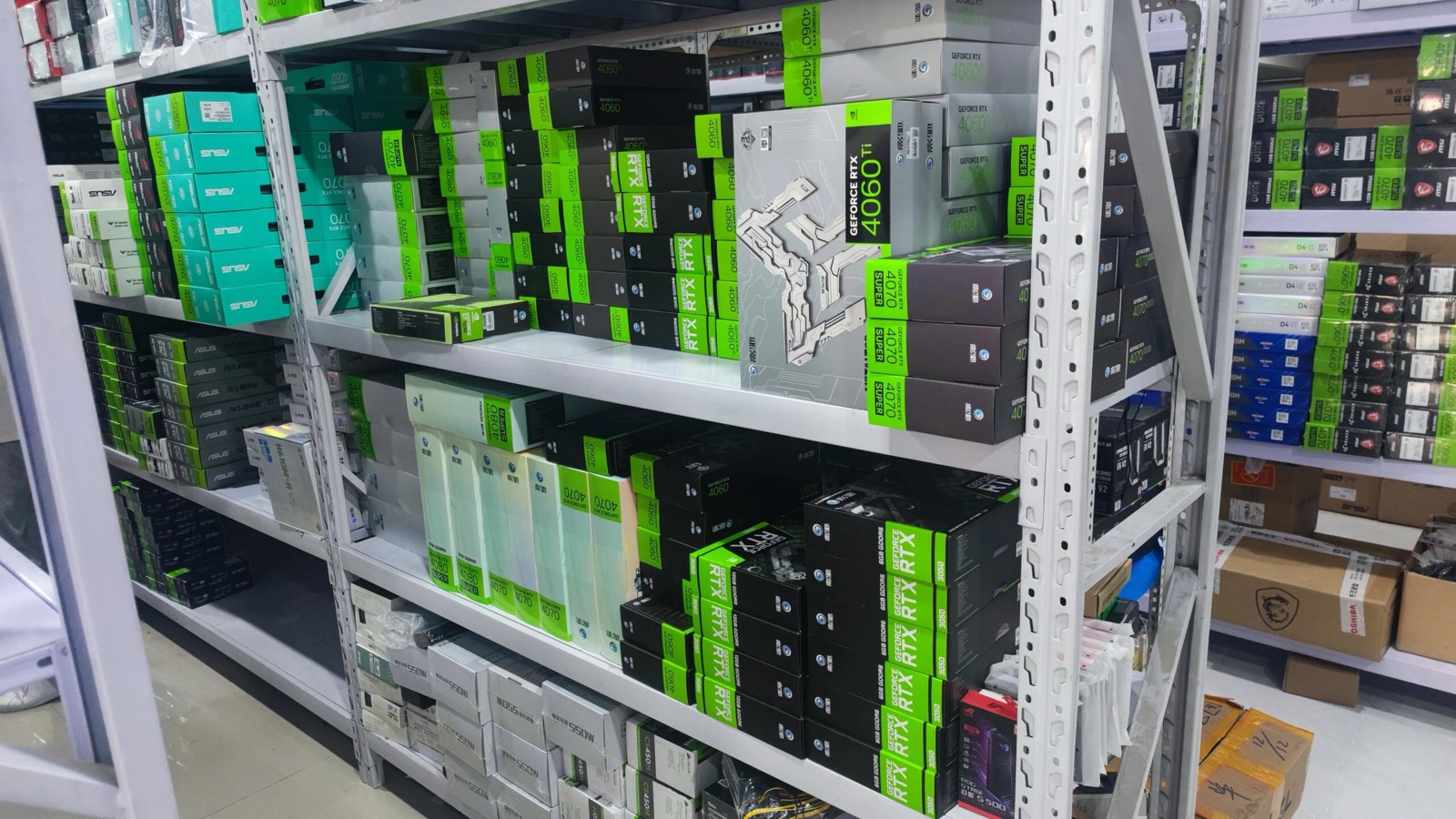 Warehouse shelving system with GPU boxes and computer parts inventory with green labels on metal shelving units