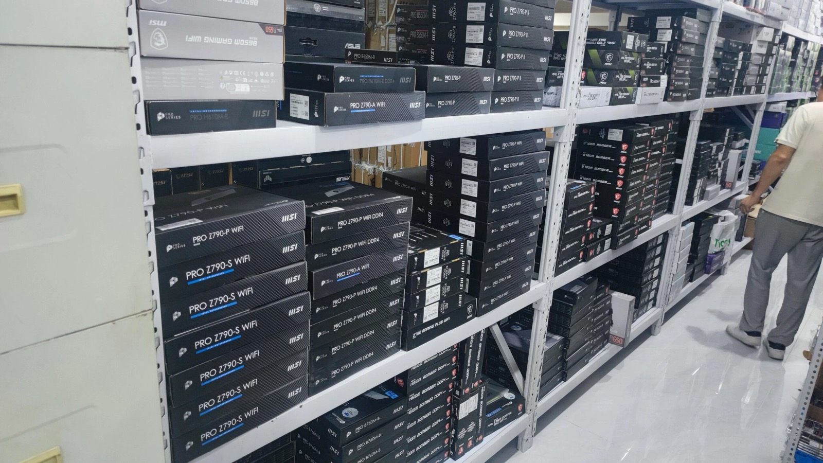 Warehouse shelving units stocked with MSI PRO Z790 motherboard boxes and computer parts inventory